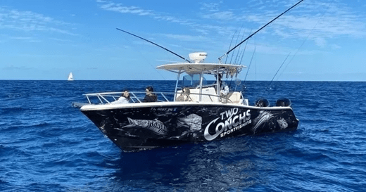 Fishing boat named 'Two Conchs' with fishing rods, on open sea with blue sky.