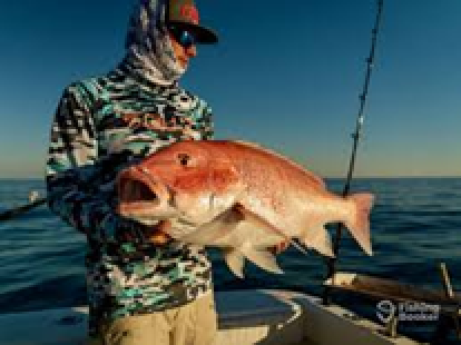 Person holding a mangrove snapper fish on a boat with ocean in the background.