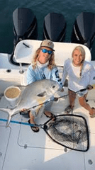 Two people on a boat holding a large fish and a fishing net.